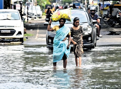 People walking through a flooded Korattur stretch on Saturday.