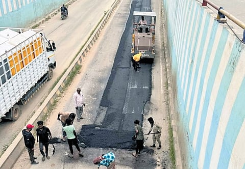 Civic workers fix a pothole-riddled stretch of road at an underpass in Bengaluru