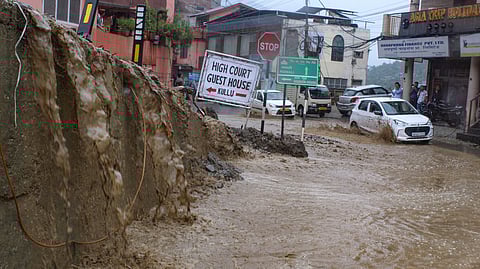 Vehicles make their way through a mud-covered road following heavy rainfall, in Kullu.