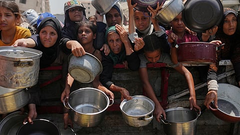 Palestinians struggle to get donated food at a community kitchen in Gaza City, northern Gaza Strip, Saturday, Aug. 16, 2025.