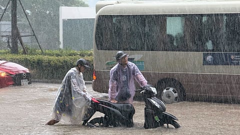 People push a motorbike through floods from heavy rains in Hanoi, after Typhoon Kajiki passed through Vietnam, Tuesday, Aug. 26, 2025.