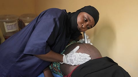 A midwife checks a pregnant woman at a facility run by aid group International Rescue Committee in Magumeri, in northeast Nigeria's Borno state, Tuesday, July 22, 2025.