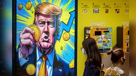People walk past a cryptocurrency exchange office with a screen featuring US President Donald Trump holding cryptocurrency coins in Hong Kong.