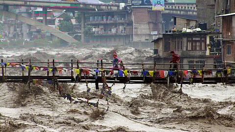 Residents run across a bridge over the flooding Beas River following incessant rains in Kullu, in Himachal Pradesh, Tuesday, Aug. 26, 2025.