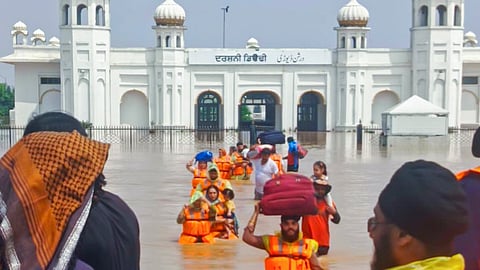 People make their way through waterlogged area of the Gurdwara Darbar Sahib, in Kartarpur Corridor, Pakistan.