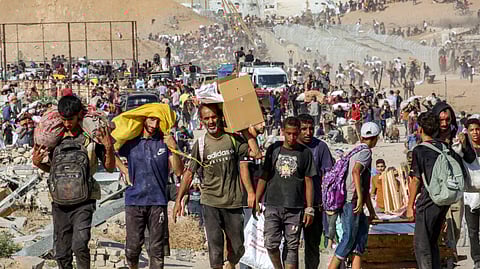 People walk with bags of humanitarian aid they received at a distribution centre run by the US and Israeli-backed Gaza Humanitarian Foundation (GHF), as they cross the so-called "Netzarim corridor" in the central Gaza Strip, on August 22, 2025.