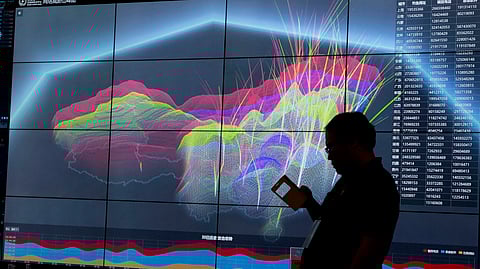 FILE - A worker using his phone is silhouetted against a computer display showing a live visualization of the online activities across China during the 4th China Internet Security Conference (ISC) in Beijing, Aug. 16, 2016. 