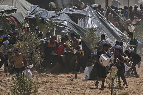 Palestinians rush to collect humanitarian aid packages from the United Arab Emirates, airdropped by parachutes into Deir al-Balah, in the central Gaza Strip, Tuesday, Aug. 19, 2025.