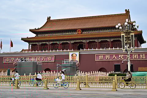 People ride past a portrait of the late communist leader Mao Zedong on Tiananmen Square, where the next military parade will take place on September 3 