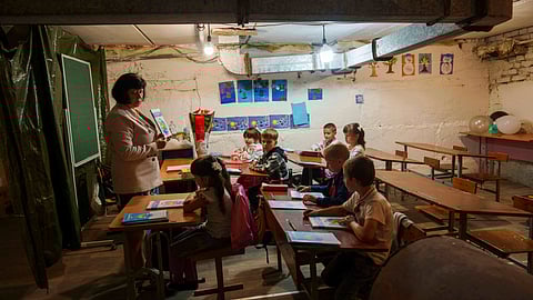 School students listen to their teacher during a lesson, in the basement of a municipal building during the first day in school in Bobryk, Sumy region, Ukraine, Monday, Sept. 1, 2025. The Bobryk school was forced to move to the basement due to endless alarms. 