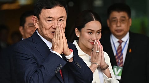 Former Thai Prime Minister Thaksin Shinawatra greets his supporters, alongside his youngest daughter—now the ousted PM—Paetongtarn Shinawatra, at Bangkok's Don Mueang airport on August 22, 2023