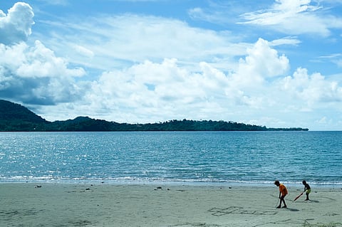 Children draw crosses on a sandy beach in Vanimo, Papua New Guinea