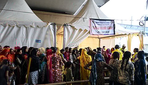 People wait in queues at a flood relief camp at Delhi-Noida road following the rise in water levels of river Yamuna, in East Delhi on Wednesday.