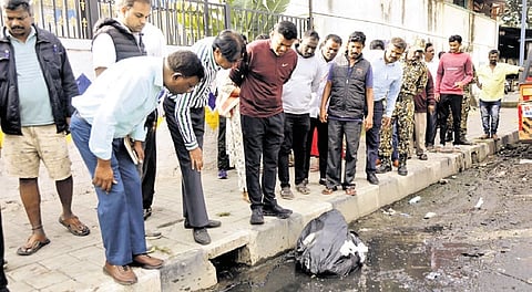 Bengaluru Central Municipal Corporation Commissioner Rajendra Cholan (maroon shirt) inspects a roadside drain in Majestic on Saturday. 