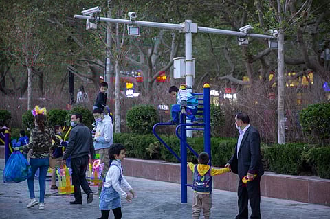 Children play on a playground near security cameras at a public square in Aksu, in western China's Xinjiang Uyghur Autonomous Region, Tuesday, April 20, 2021.