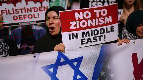 People shout slogans during a protest against Israel's war in Gaza, in Istanbul, Turkey, Saturday, June 21, 2025. The board on the left reads, in Turkish: "Get out of Palestine."