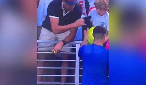 CEO of Drogbruk Piotr Szczerek (L) snatching Polish star Kamil Majchrzak's match-worn cap from a young fan.