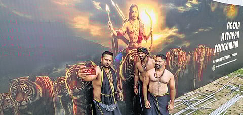 Ayyappa devotees beside a board at Pampa set up for the Global Ayyappa Sangamam on Saturday  