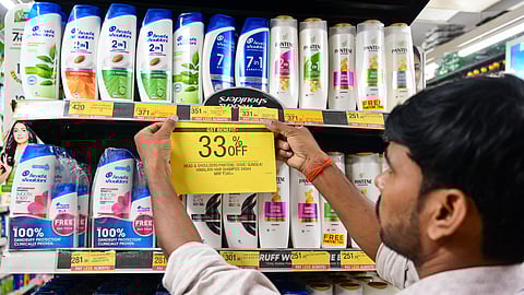 A man puts a 33% off poster on shampoo bottles, at a shop, in Prayagraj, Monday, Sept. 22, 2025. The new GST rates came into effect.