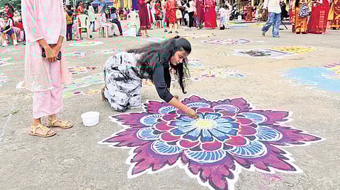 Women draw rangoli during the Dasara Rangoli competition outside the Amba Vilas Palace in Mysuru on Tuesday