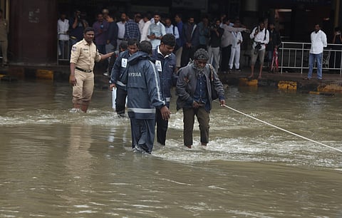 HYDRAA officials help a man to cross the flooding road at MGBS in Hyderabad following the Musi River overflowing.