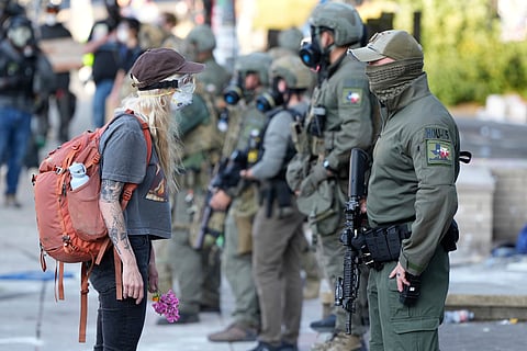 A woman stands off with a law enforcement officer wearing a Houston Field Office Special Response Team patch outside the U.S. Immigration and Customs (ICE) building during a protest Saturday, June 14, 2025, in Portland, Ore.