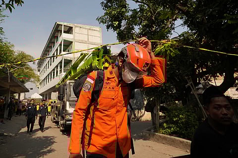 A rescuer walks near the Islamic boarding school where a building collapsed in Sidoarjo, East Java, Indonesia, Saturday, Oct 4, 2025.