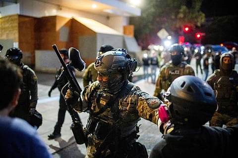 Police and Federal officers stand guard an area by the U.S. Immigration and Customs Enforcement facility in Portland, Ore. on Sunday, Oct. 5, 2025.