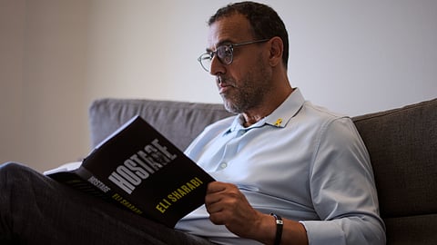 Eli Sharabi, who was abducted during the cross-border attack on Israel on Oct. 7, 2023, and held hostage by Hamas for 16 months, poses with his new book "Hostage" for a photo in Herzliya