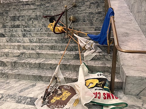 In this undated photo provided by the Department of Enterprise Services, a Washington state government agency, county flags sit burned on marble steps inside the Capitol in Olympia, Wash., after an intruder broke in an vandalized the Legislative building on the evening of Oct 5, 2025.
