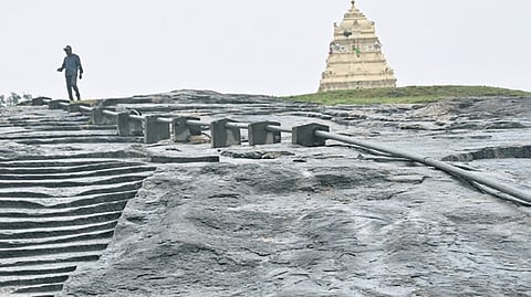 A man climbs down the Lalbagh rock on a rainy day in Bengaluru.