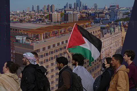 Students walk past a poster of the skyline of London as they take part in demonstration holding banners, placards and flags during an Inter-university march for Gaza in London, Tuesday, Oct. 7, 2025