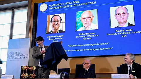 Chair of the Nobel Committee for Chemistry Heiner Linke makes a demonstration, next to Secretary General of the Swedish Academy of Sciences Hans Ellegren, and Member of the Nobel Committee for Chemistry Olof Ramstrom, right, after they announce Susumu Kitagawa, Richard Robson and Omar Yaghi, on screen behind, as the recipients the Nobel Prize in Chemistry, at the Nobel Assembly of the Karolinska Institutet, in Stockholm, Sweden, Wednesday, Oct. 8, 2025.