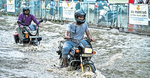 Commuters ride through the flooded NH 16 service road near Iskcon temple.