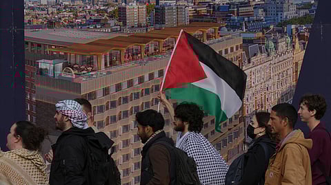 Students walk past a poster of the skyline of London as they take part in demonstration holding banners, placards and flags during an Inter-university march for Gaza in London, Tuesday, Oct. 7, 2025