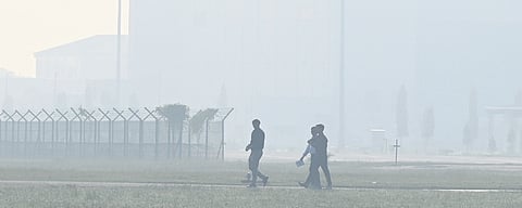 Men take a stroll through an area enveloped in mist early morning in Delhi.