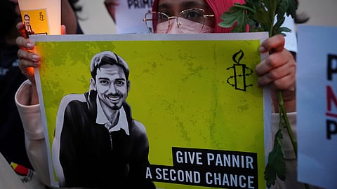 An activist holds a candle and a placard during a vigil against the impending execution of Malaysian national Pannir Selvam Pranthaman, sentenced to death for trafficking heroin into Singapore, outside the Singaporean embassy in Kuala Lumpur, Malaysia, Feb. 19, 2025.