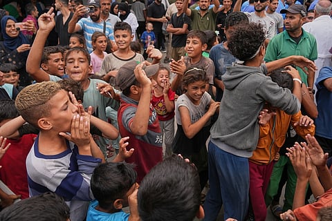 Displaced Palestinians watch smoke rise after Israeli military strikes as they gather on the coastal road near Wadi Gaza, in the central Gaza Strip, Thursday, Oct. 9, 2025.