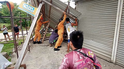 In this photo provided by the Bureau of Fire Protection, firefighters and residents hold on a toppled structure following a strong earthquake in Davao Oriental province, southern Philippines on Friday Oct. 10, 2025.