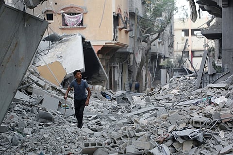 Displaced Palestinians walk amid destroyed buildings in the heavily damaged Sheikh Radwan neighborhood in Gaza City, Saturday, Oct. 11, 2025, after Israel and Hamas agreed to a pause in their war and the release of the remaining hostages.