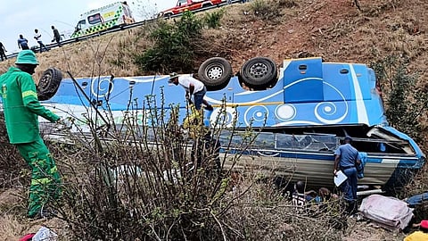 In this photo made available by the South African Department of Transport and Community Safety, Police officers and emergency rescue workers search for victims from a bus lying upside down in the embankment, in Louis Trichardt, South Africa, Sunday, Oct. 12, 2025