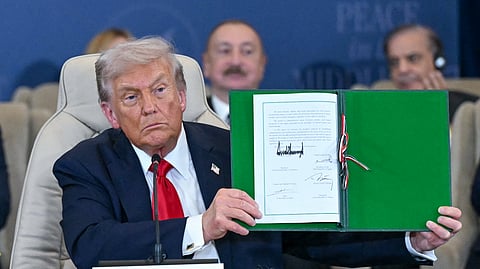 President Donald Trump poses with the signed agreement at a world leaders' summit on ending the Gaza war, in Sharm el-Sheikh, Egypt, Monday, Oct. 13, 2025.