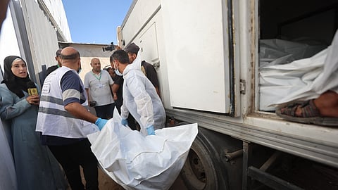 Morgue workers unload the bodies of Palestinians that had been in Israeli custody, after they were transported by Red Crescent vehicles and refrigerated trucks, to the Nasser hospital in Khan Yunis in the southern Gaza Strip on October 15, 2025.