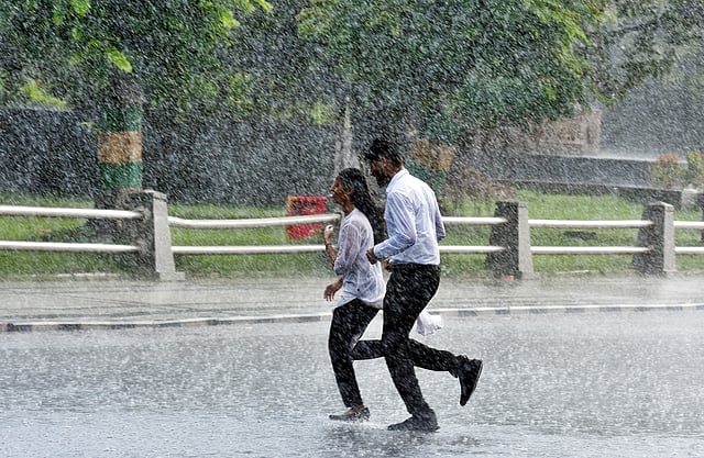 People walk through rain showers along Rajaji Salai near Fort St. George on Wednesday afternoon, marking the onset of the northeast monsoon in Chennai. 