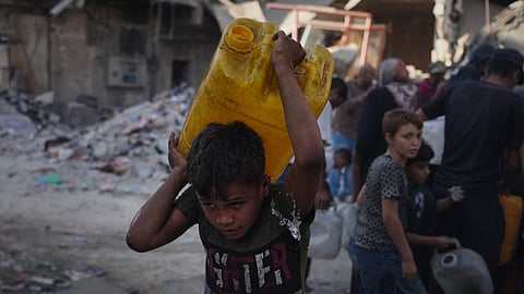 Palestinians carry jerrycans with water they collect from a truck in Gaza City, Thursday, Oct. 16, 2025.