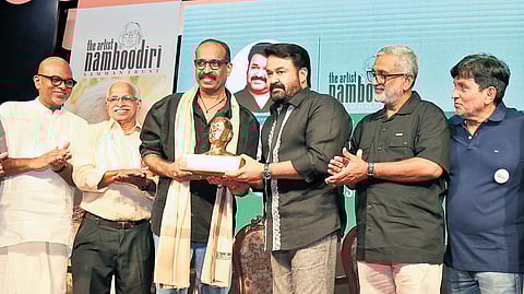 Actor Mohanlal presents the first Artist Namboodiri Samman to C Bhagyanath in Kochi. Notable attendees included Babu Joseph, K C Narayanan, and others.
