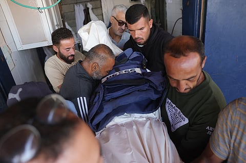Palestinian men carry the body of broadcast journalist Ahmad Abu Mteir, killed in an Israeli strike on a house used by journalists in the town of Zuwaida in the central Gaza Strip the previous day, during preparations for his burial at the Shuhada al-Aqsa hospital in Deir al-Balah on October 20, 2025.