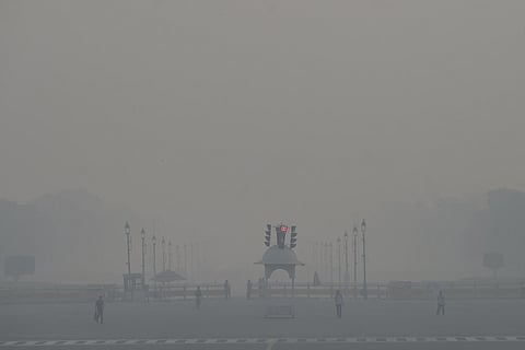 People move along a foundation pathway on a hazy morning as thick smog engulfs the city, at Man Singh Road in New Delhi, Wednesday.