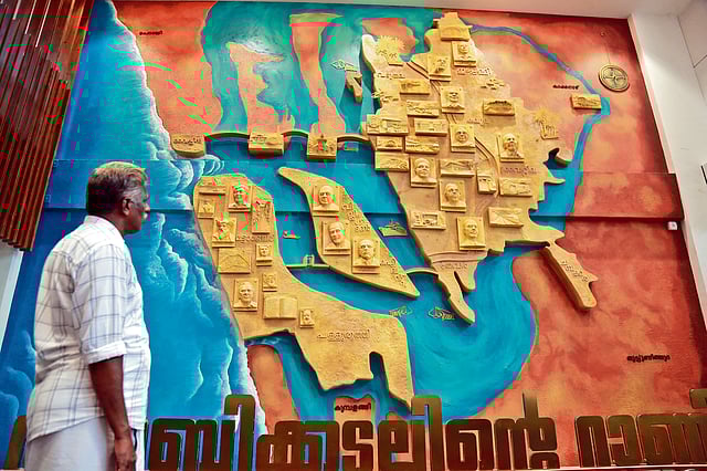 A man looks at a Kochi map installation with inscriptions highlighting luminaries of the city.