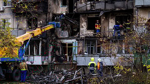 Firefighters work at a destroyed apartment building.